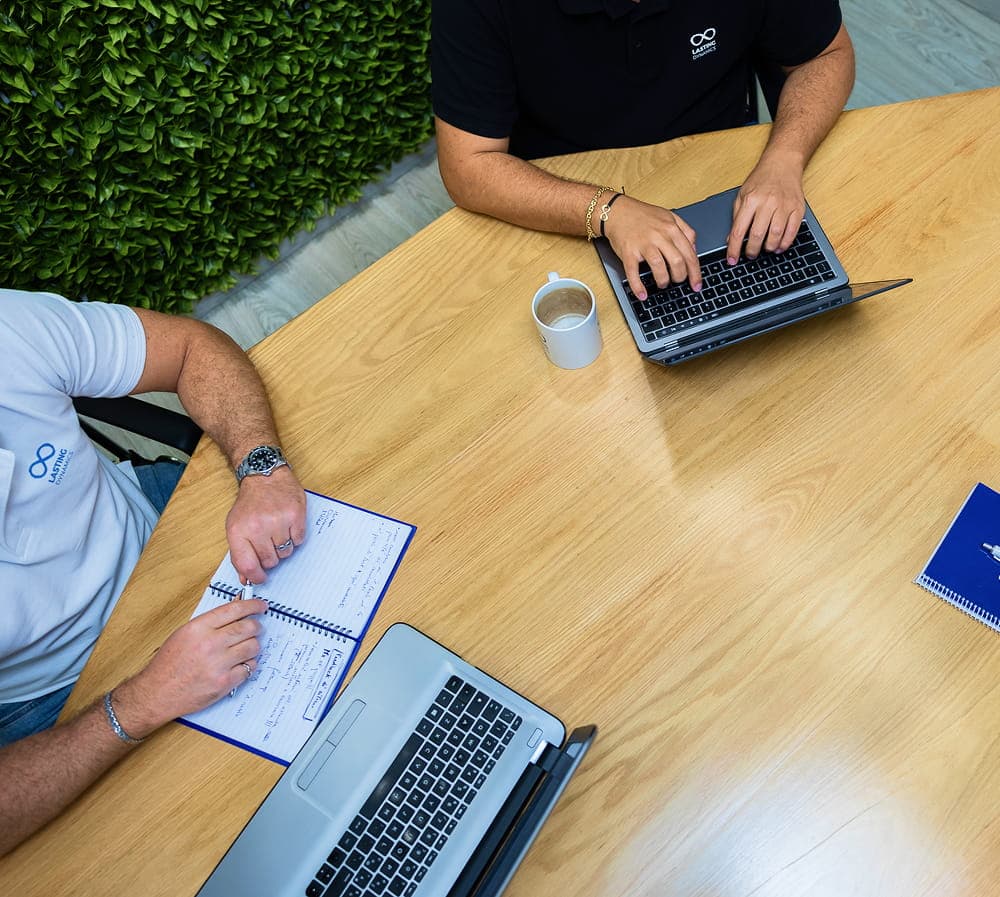 Lasting Dynamics team collaborating on hybrid software development at a desk with laptops